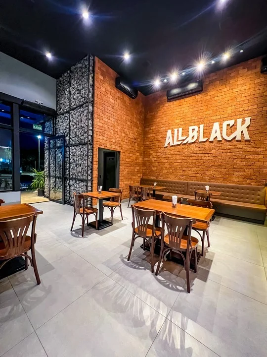 Salão com parede de tijolo e o letreiro All Black em relevo